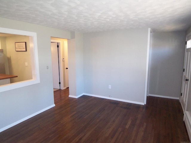 empty room featuring dark wood-type flooring and a textured ceiling