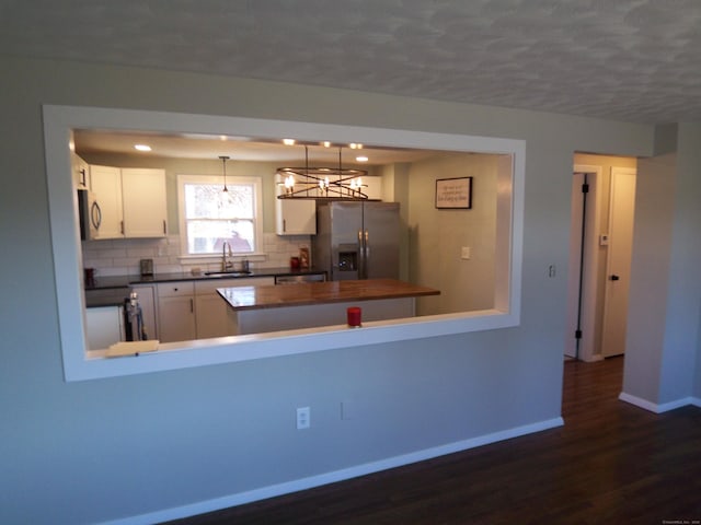 kitchen featuring white cabinetry, sink, stainless steel fridge with ice dispenser, dark hardwood / wood-style flooring, and pendant lighting