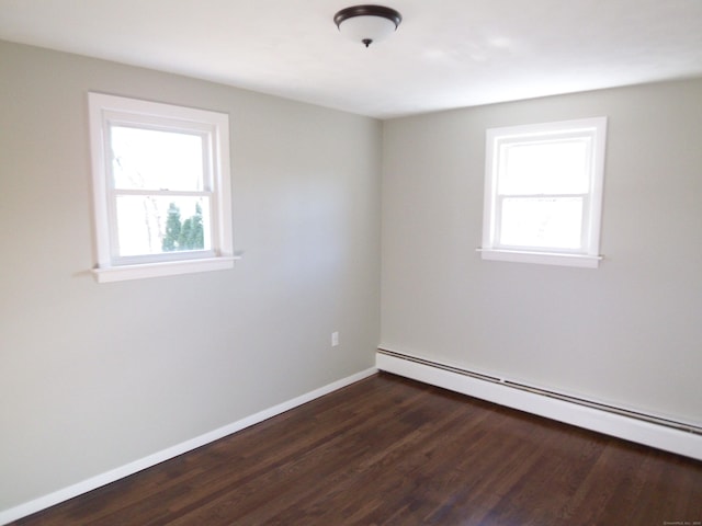 empty room with dark wood-type flooring and a baseboard heating unit