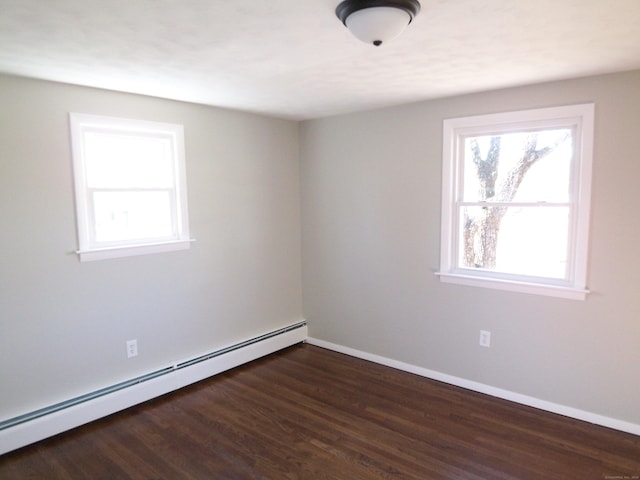 spare room with dark hardwood / wood-style flooring and a baseboard heating unit