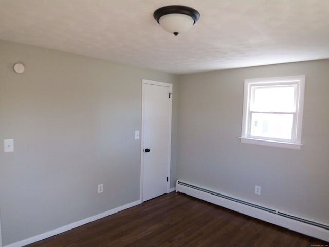 spare room with baseboard heating and dark wood-type flooring