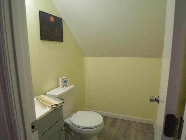 bathroom featuring toilet, wood-type flooring, vanity, and vaulted ceiling