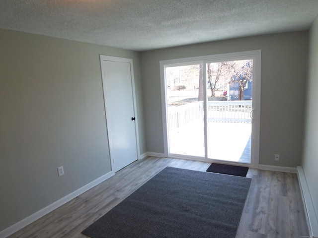 empty room with light hardwood / wood-style floors and a textured ceiling