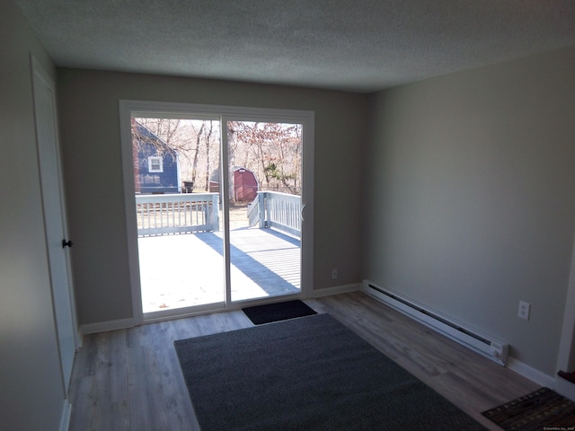 entryway with a textured ceiling, light hardwood / wood-style flooring, and a baseboard heating unit