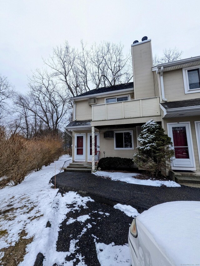 view of front of property with a wall mounted air conditioner and a balcony