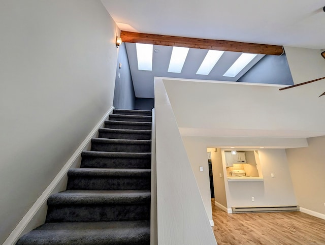 staircase featuring hardwood / wood-style floors, high vaulted ceiling, a skylight, a baseboard heating unit, and beam ceiling