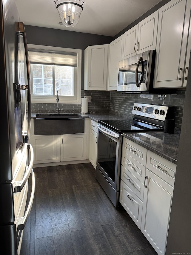 kitchen with appliances with stainless steel finishes, dark hardwood / wood-style floors, white cabinetry, and sink