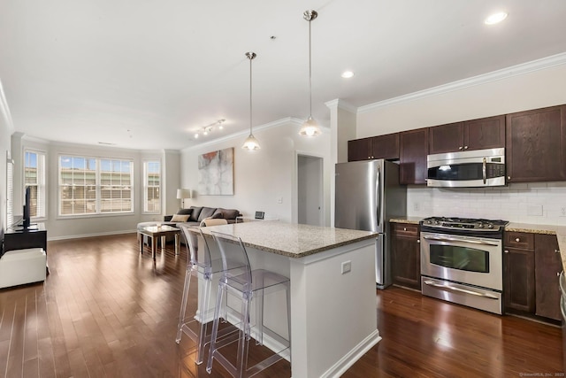 kitchen with a kitchen island, backsplash, appliances with stainless steel finishes, and dark wood finished floors