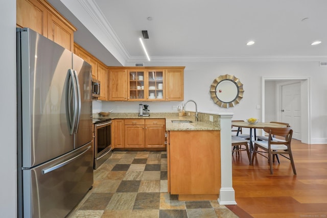 kitchen with a peninsula, crown molding, stainless steel appliances, and a sink