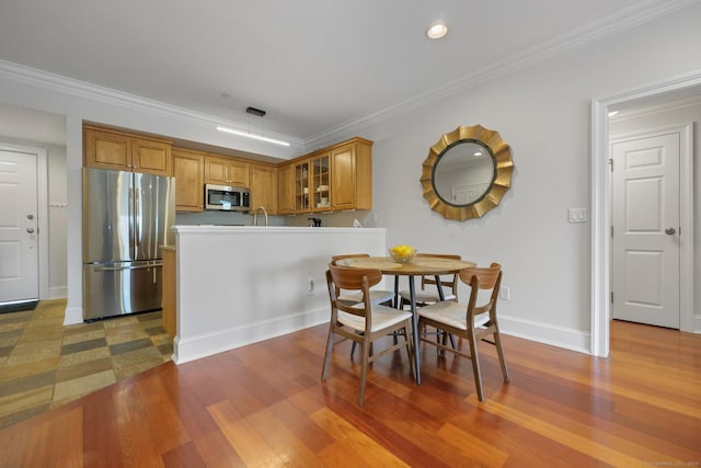 dining space with ornamental molding, baseboards, and wood finished floors