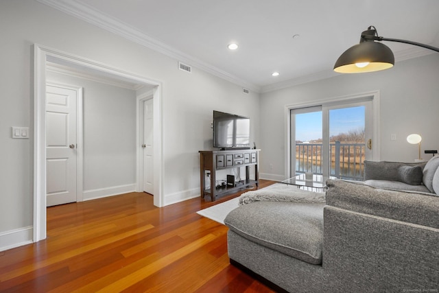 living room featuring ornamental molding, visible vents, baseboards, and wood finished floors