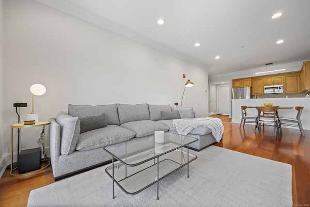 living room featuring light wood-type flooring, baseboards, ornamental molding, and recessed lighting