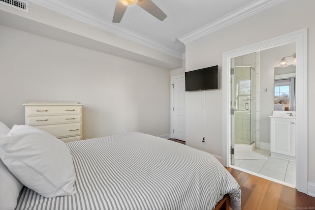 bedroom featuring crown molding, visible vents, connected bathroom, wood finished floors, and baseboards