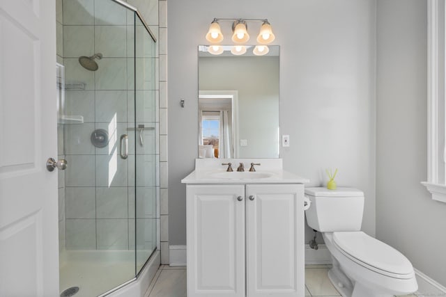 bathroom with vanity, a shower stall, toilet, and baseboards