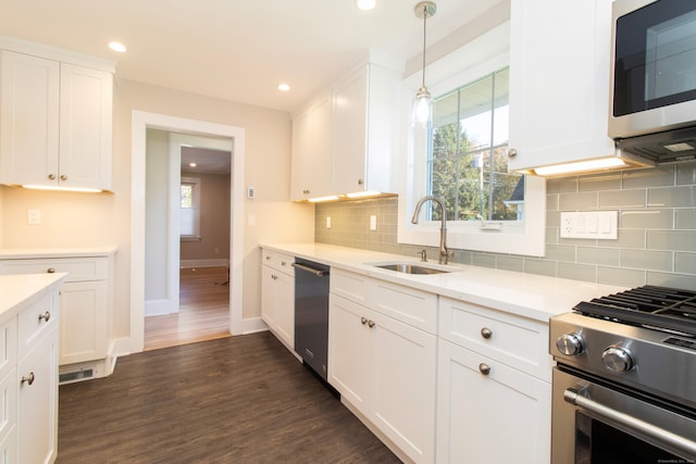 kitchen with white cabinetry, appliances with stainless steel finishes, decorative light fixtures, and sink