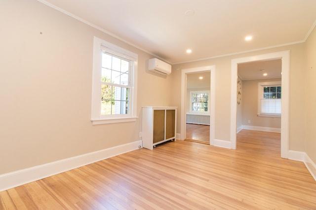 empty room featuring ornamental molding, a wall mounted air conditioner, and light hardwood / wood-style flooring