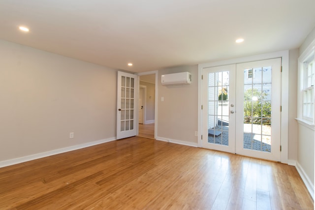 spare room with light hardwood / wood-style flooring, a wall mounted AC, and french doors