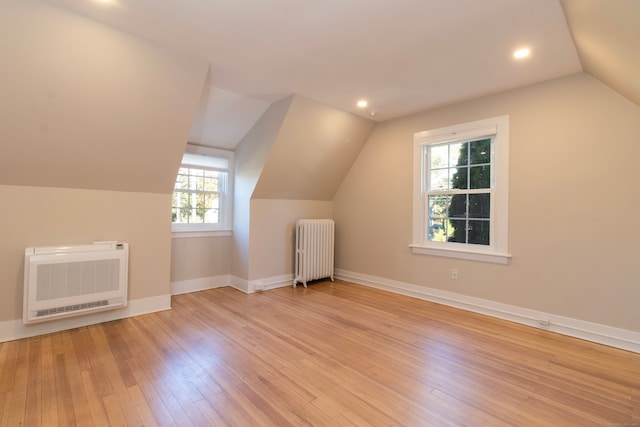 bonus room with lofted ceiling, radiator heating unit, heating unit, and light wood-type flooring