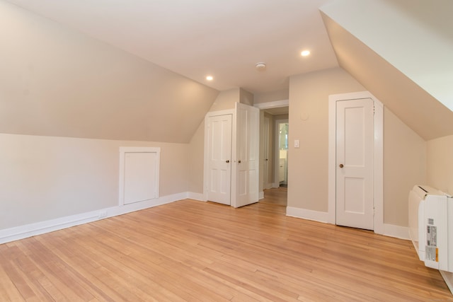 bonus room featuring heating unit, light hardwood / wood-style flooring, and vaulted ceiling