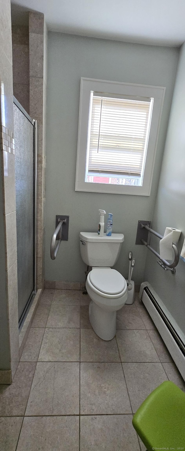 bathroom featuring toilet, tile patterned flooring, a shower with door, and a baseboard heating unit