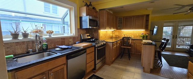 kitchen featuring stainless steel appliances, french doors, decorative backsplash, sink, and ceiling fan