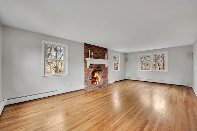 unfurnished living room featuring a fireplace, a baseboard radiator, plenty of natural light, and light hardwood / wood-style floors