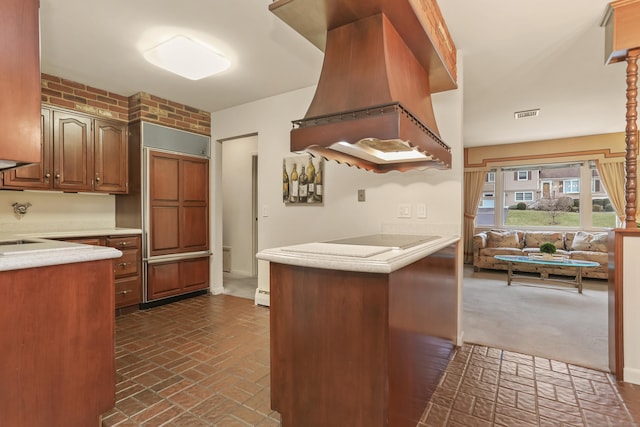 kitchen featuring custom exhaust hood, black electric stovetop, and kitchen peninsula