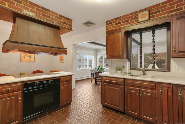 kitchen with sink, oven, custom range hood, cooktop, and a baseboard radiator