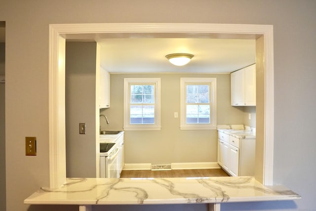 kitchen featuring light stone counters, sink, white cabinetry, and white range with electric cooktop