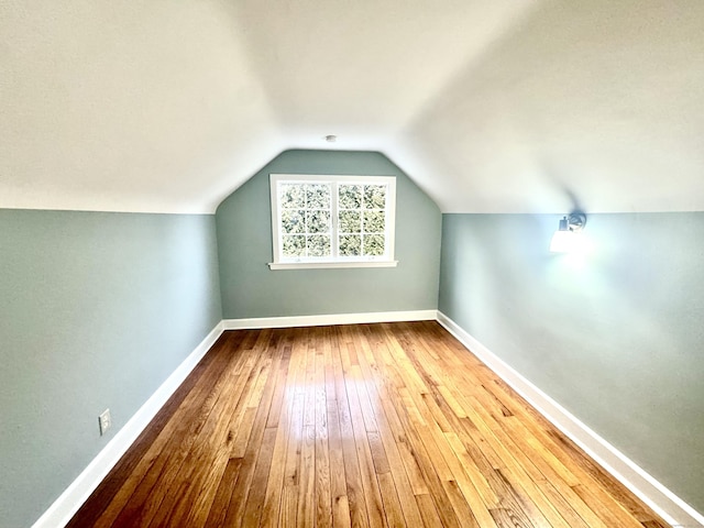 additional living space with vaulted ceiling and hardwood / wood-style flooring