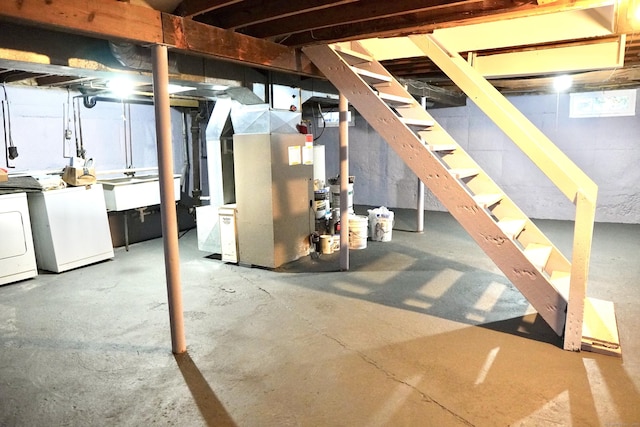 basement featuring heating unit, sink, and washer and dryer