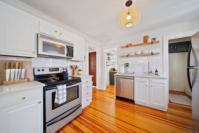 kitchen with white cabinetry, sink, stainless steel appliances, tasteful backsplash, and decorative light fixtures