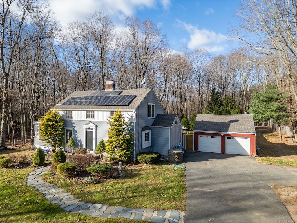 view of side of home featuring solar panels, a garage, and an outbuilding