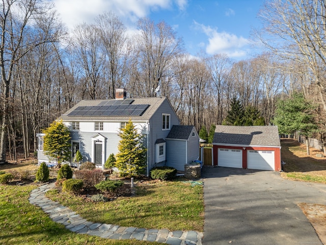 view of side of home featuring solar panels, a garage, and an outbuilding