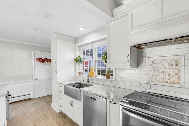 kitchen with sink, light stone counters, appliances with stainless steel finishes, white cabinets, and light wood-type flooring