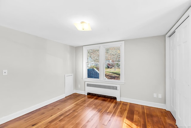 unfurnished room featuring radiator and hardwood / wood-style floors