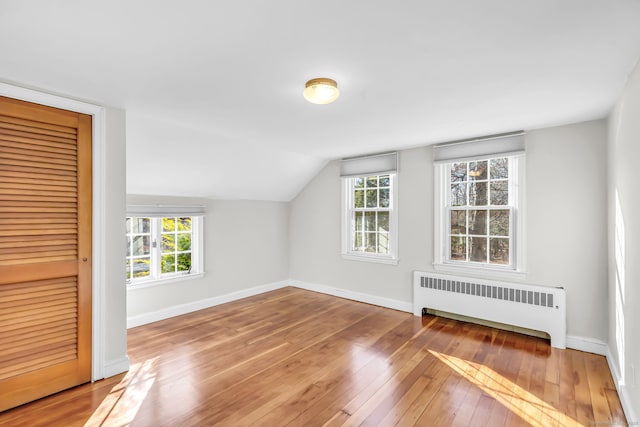 bonus room featuring radiator heating unit, vaulted ceiling, and wood-type flooring