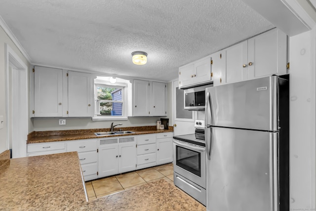 kitchen with sink, light tile patterned floors, a textured ceiling, white cabinetry, and stainless steel appliances