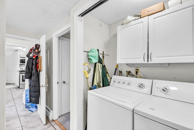 laundry room featuring cabinets, a textured ceiling, a baseboard heating unit, washer and dryer, and light tile patterned floors