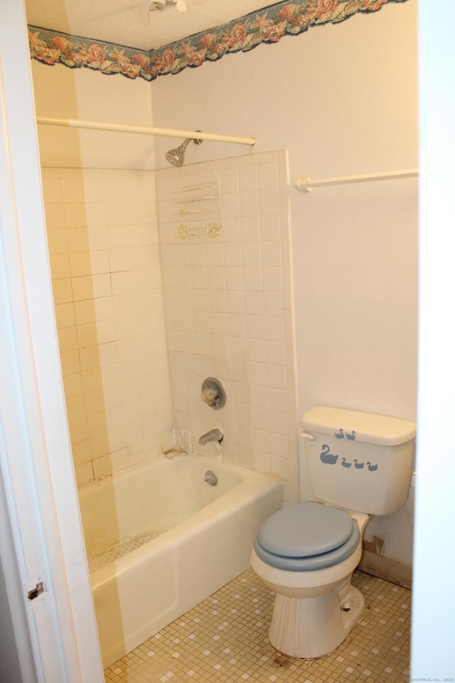 bathroom with tile patterned flooring, tiled shower / bath combo, and toilet