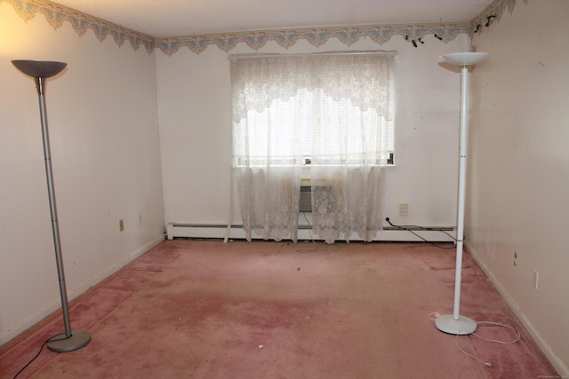 carpeted spare room with a baseboard heating unit