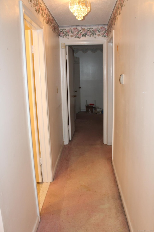 hallway featuring light carpet and a textured ceiling