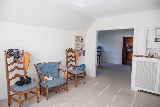 sitting room with built in shelves, carpet floors, and vaulted ceiling