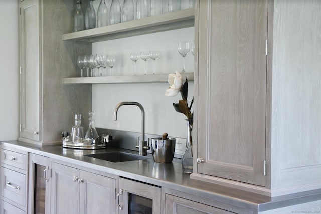 bar with beverage cooler, light brown cabinets, and sink