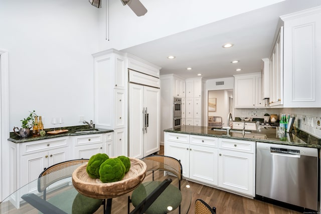 kitchen with stainless steel appliances, dark stone countertops, white cabinets, and sink