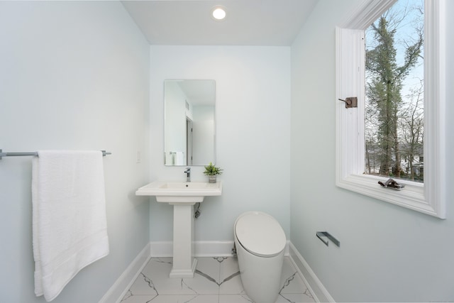 bathroom featuring toilet, sink, and plenty of natural light