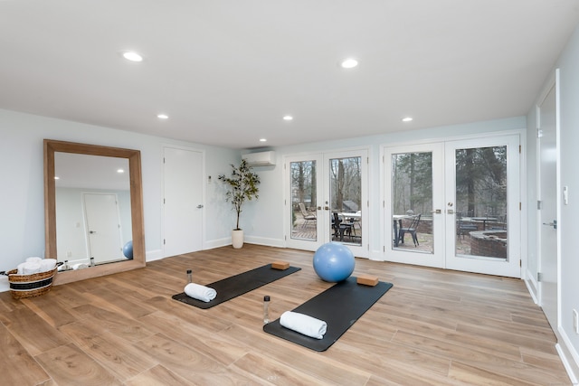 workout room with an AC wall unit, french doors, and light hardwood / wood-style floors