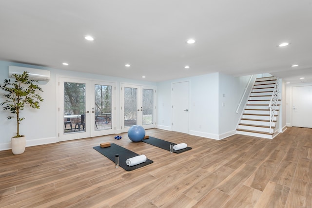 workout area featuring an AC wall unit, french doors, and light hardwood / wood-style floors