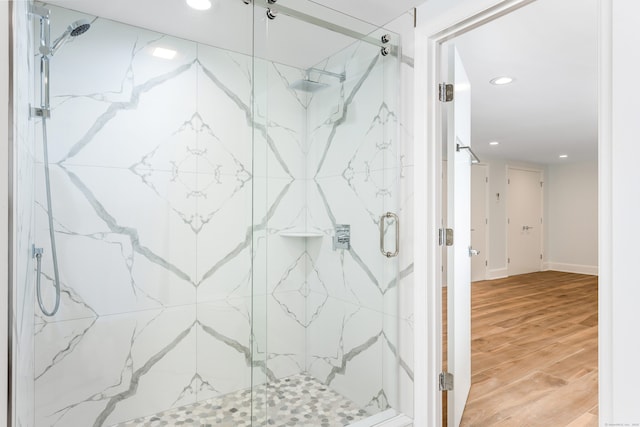 bathroom featuring a shower with shower door and wood-type flooring