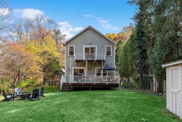 back of house featuring a lawn, a deck, a balcony, and a fire pit